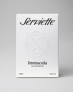 A white rectangular box for Serviette Immacula Eau de Parfum, photographed against a neutral light gray background. The box features black text and an embossed circular emblem in the center.
