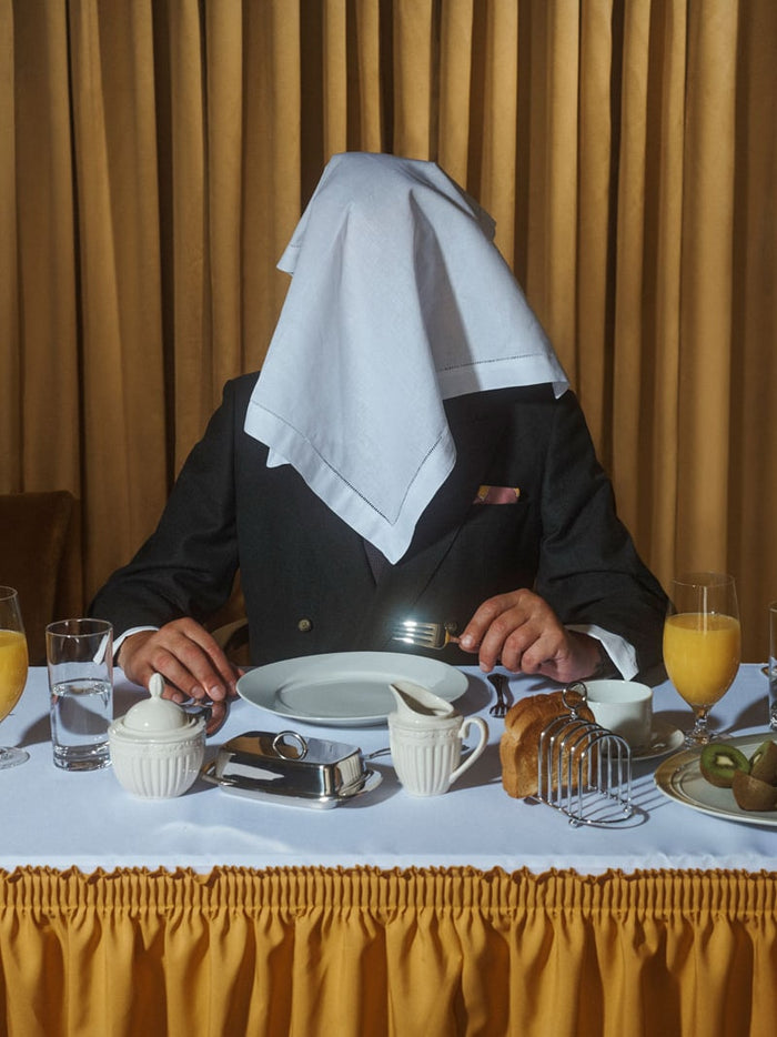 Hero image with person sitting at dinning table with serviette over head.