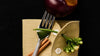 Fork, knife, and garnishes on a folded napkin with a dark background