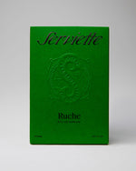 Green packaging of Serviette Ruche perfume with embossed logo on a gray background